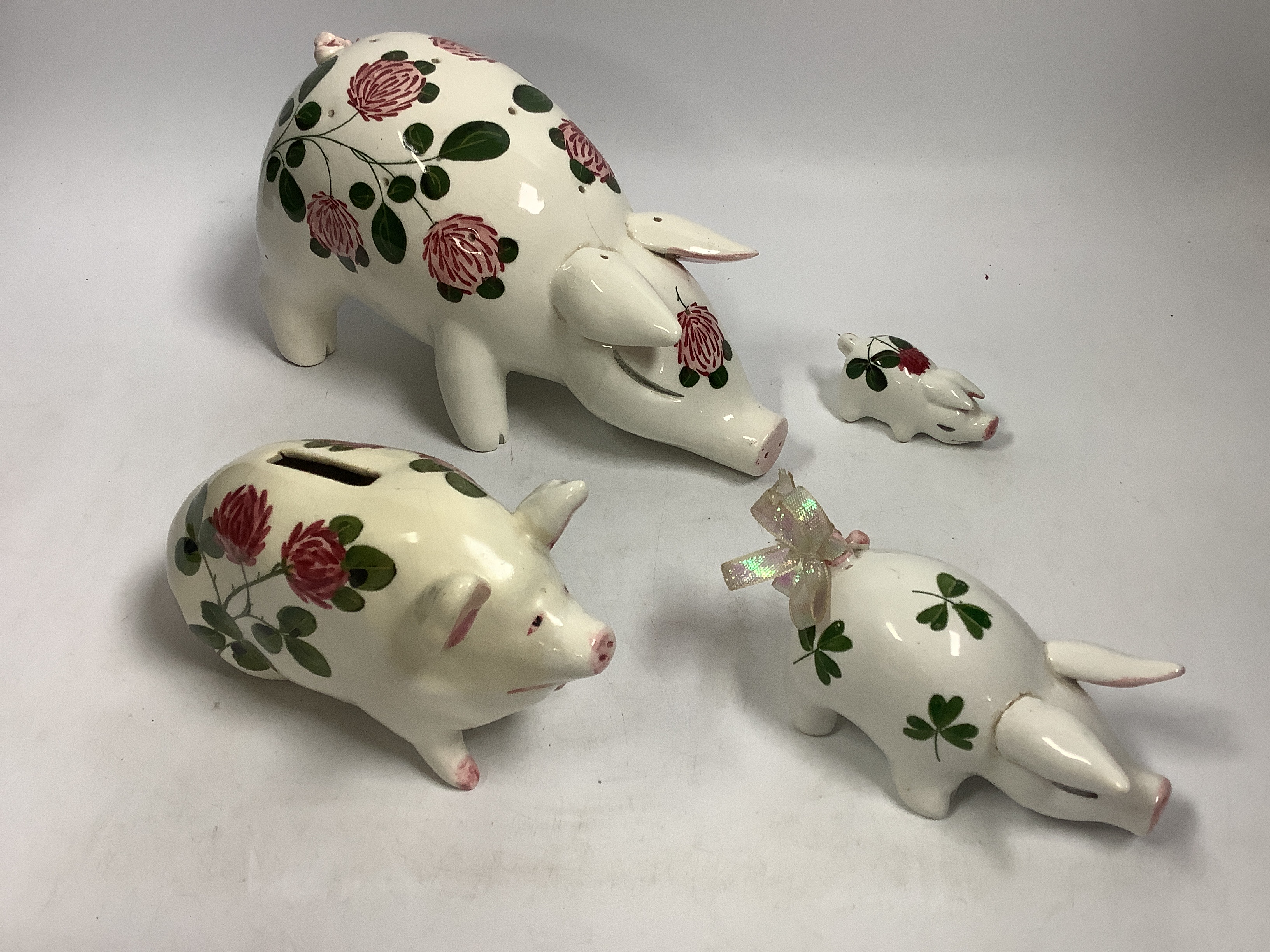 A Plichta rose decorated pig money box, 16cm, and a Plichta rose decorated hatpin holder pig, 23cm and two other Plichta pigs